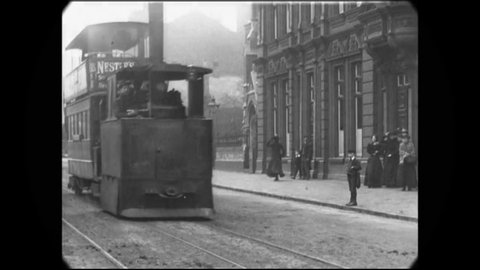 CIRCA 1902 - Buses and trolleys pass by a camera in an Irish city, and young boys stop to ogle the camera.