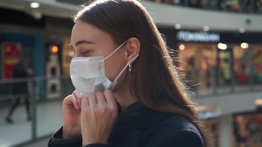 Close portrait serious worried young slavic woman in public place, shopping mall, wears face protecting mask. Pandemic N1H1 coronavirus, virus protection. Concept of safety and health life. Quarantine Royalty-Free Stock Footage #1049194096