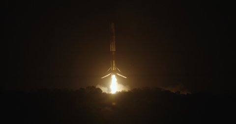 CAPE CANAVERAL, FL circa March 2020 - SpaceX Falcon 9 first-stage booster descends back to landing zone. Extends legs and lands at night in the dark. 4K at 120 fps slow motion.