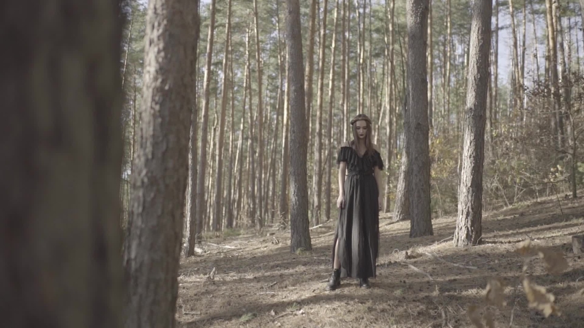 Girl in a black dress in the autumn forest with a pumpkin