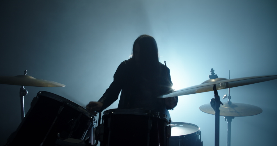 An authentic drummer playing a solo in a band, hitting the drums while playing rock or metal music, silhouetted on smoked stage - band, music concept 4k footage Royalty-Free Stock Footage #1049208751