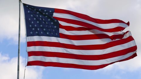 SUPER SLOW MOTION: American Flag blowing in the wind with a blue sky background. USA American Flag. Waving United states of America famous flag in front of blue sky. Independence Day -American concept