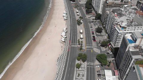 Rio de Janeiro, Brazil - March 27, 2020: Near empty Copacabana beach and boulevard with the decorated sidewalk and colourful pavement during the COVID-19 Coronavirus outbreak at a sunny summer midday