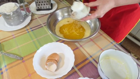 Simple food, pie making. The woman adds sour cream and baking powder to the melted butter in the beaten eggs with sugar. Close up.