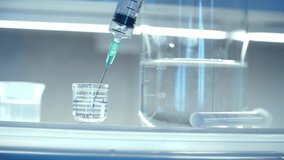 Close up of syringe in laboratory takes medical solution from beaker for chemical analysis. Сoncept of pharmaceutical research. Concept of Coronovirus Vaccine Development. - Powered by Shutterstock - Get 15% off with code: PIKWIZARD15