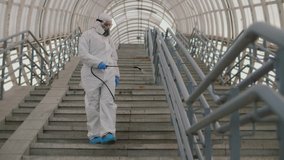 Virologist in protective suit disinfects surface, sprays liquid chemicals on handrails. Sanitary measures against coronavirus in public place Covid-19 coronavirus spreading prevention - Powered by Shutterstock - Get 15% off with code: PIKWIZARD15