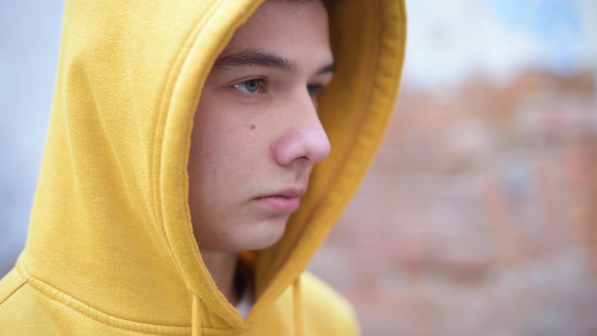 a teenager in a yellow sweatshirt looks in front of him, close-up