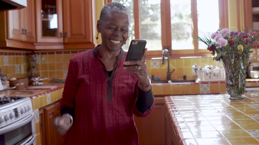 Happy old African American mature black woman pumping her arm in the air while using her smart phone celebrating success Royalty-Free Stock Footage #1049262589