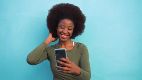 Young black woman using smart mobile phone - African girl laughing and smiling using web app on cellphone - Female lifestyle and technology concept