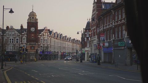Crouch End, London / UK - March 24 2020: Corona Virus Lockdown. A few cars pass through quite Streets of Crouch End Broadway. Clock Tower.