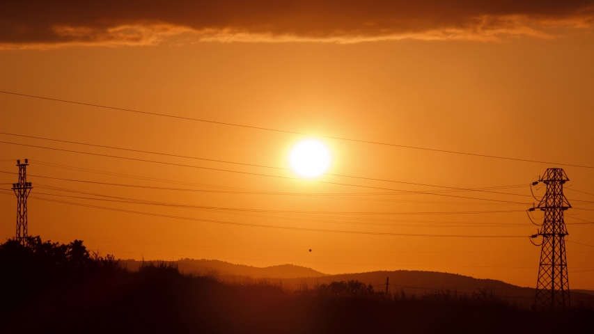 Sunset time lapse with pylon and mountain silhouette. Sun is going down fastly. 4K video without sound.