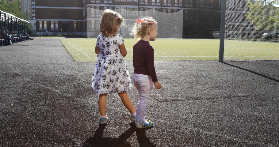 girls on the football field run to the distillery with each other on artificial grass in the sunlight.