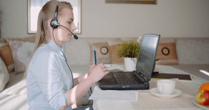 Sales representative in headset speaking to client and making video conference call on laptop.