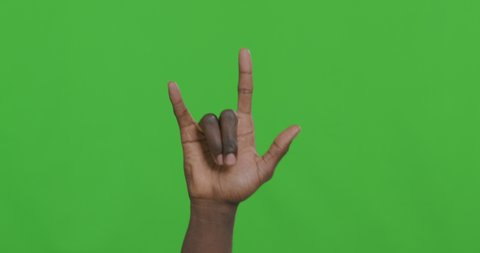Rock-n-roll concept. Black male hand waving with horns gesture, green chroma key background