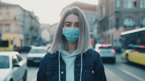 Close up view of a sad young woman wearing protective mask on the street road outdoor. Concept of health and safety life N1H1 covid19 coronavirus virus protection pandemic cars city