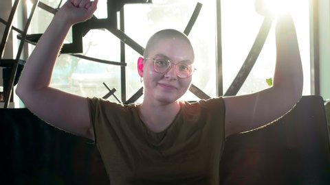 Lesbian bald girl rejoices in victory over cancer or hiv. Raises his hands up, celebrates the victory, healed. Strong and happy breast cancer survivior woman - breast cancer awareness concept.