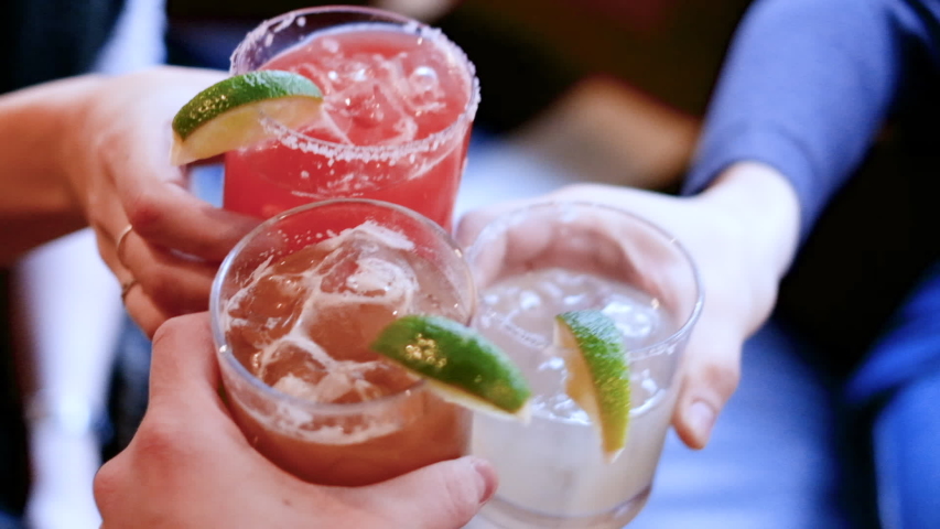Friends toasting, saying cheers holding tropical blended fruit margaritas. Watermelon, tamarind, and lime drinks and cocktails. Royalty-Free Stock Footage #1049328481