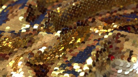 Gold sequins fabric. Holiday abstract glitter background with blinking lights. Fashion luxury fabric glitter, spangles, paillettes