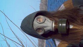 Portrait of a girl in a gas mask near the river. Personal safety concept for infectious epidemics, chemical or radioactive contamination. 4K