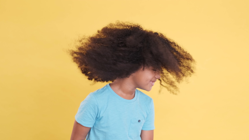 Happy African American Little Child Shaking Head on yellow Background. Lush Curls, Expressive emotions, Positive Feelings, Good Mood. Funny Playful Female Kid. Slow Motion, CloseUp. Royalty-Free Stock Footage #1049354749