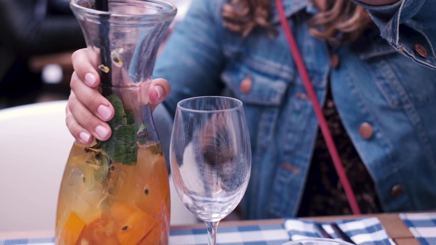 Woman pouring sangria from a pitcher at a restaurant.  Brunch with friends. Royalty-Free Stock Footage #1049371327