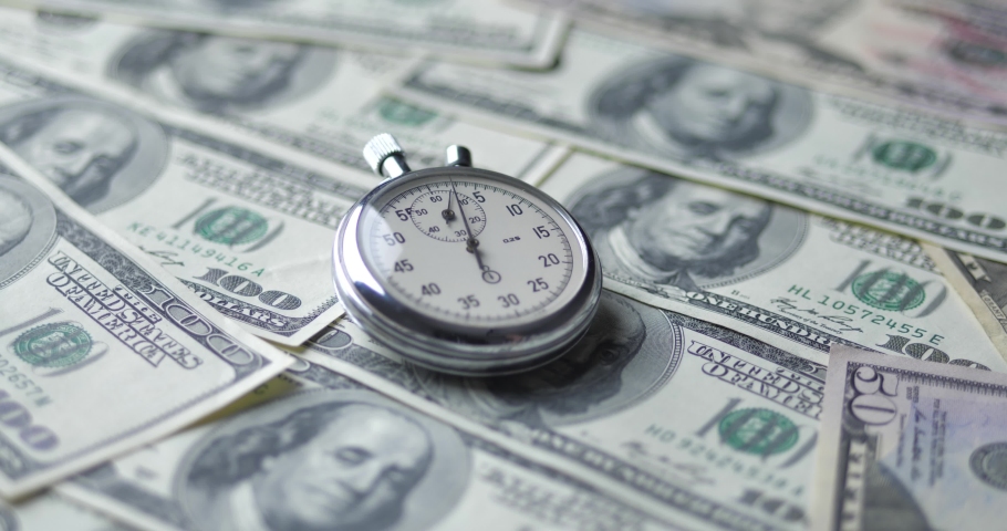 The stopwatch lies on the dollars. Time is money concept.