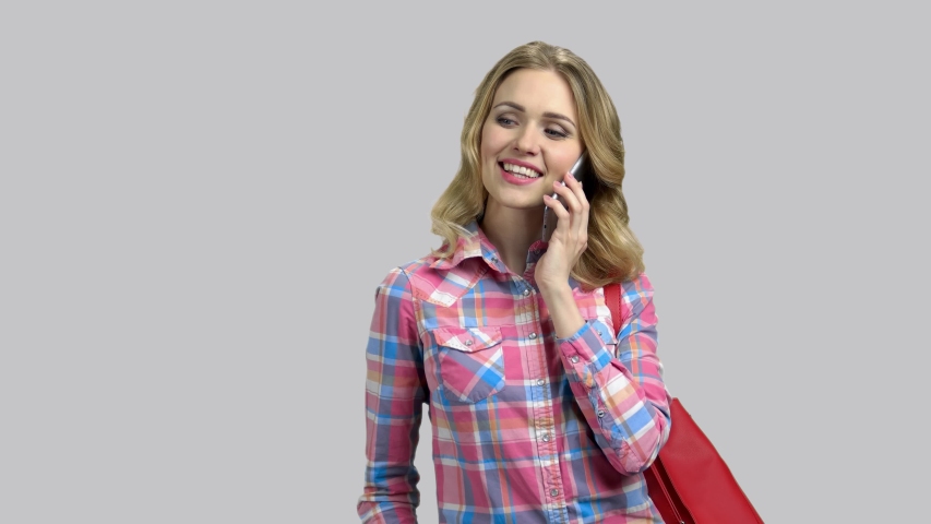 Happy young girl talking with her beloved boyfriend on phone. Glamour blond girl in love, grey isolated background.