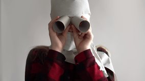 funny video - quarantined due to an epidemic of coronavirus. girl in a mask from toilet paper posing on a gray background.