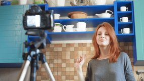 Girl food blogger influencer is recording a video or podcast in the kitchen. Dancing in front of the camera, having fun with subscribers.