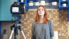Food blogger girl influencer is recording a video or podcast in the kitchen. Makes lifestyle blog vlog, shows a heart sign from hands. A woman communicates with subscribers, asks to like the video