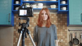 Food blogger girl influencer is recording a video or podcast in the kitchen. Makes lifestyle blog vlog about healthy and unhealthy foods. A woman communicates with subscribers, asks to like the video