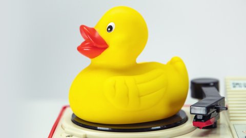 Vintage record player turning with yellow rubber duck on top spinning around.