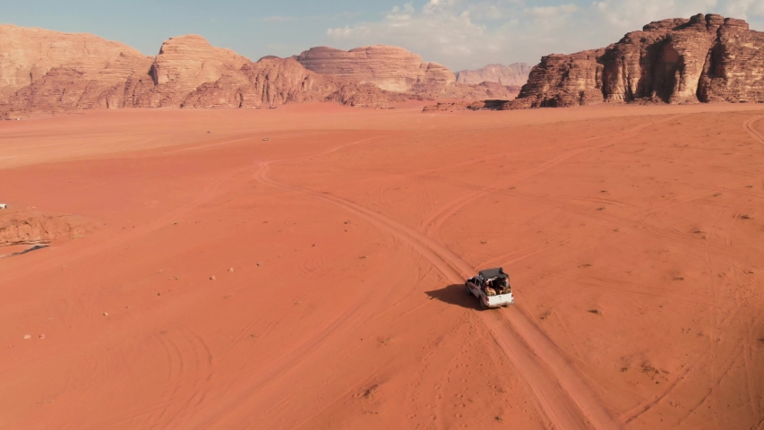 Aerial shot from above with group of people driving in off road vehicle in the middle of the Wadi Rum desert, Jordan