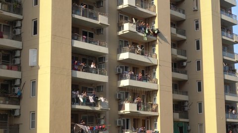 Gurgaon, Delhi, India - circa 2020 : Locked on shot of India families men, women, children clapping cheering form their balconies as they celebrate the contribution of essential workers like doctors