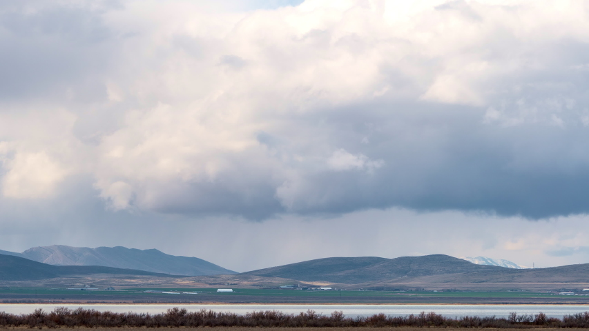 Storm clouds rolling over hills past lake as storm is brewing.