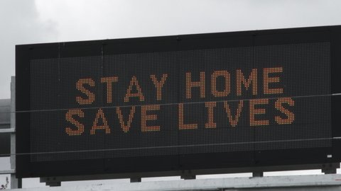 Camera zoom in and out variations on road sign reading "Stay Home, Save Lives" during the COVID-19 corona virus pandemic.