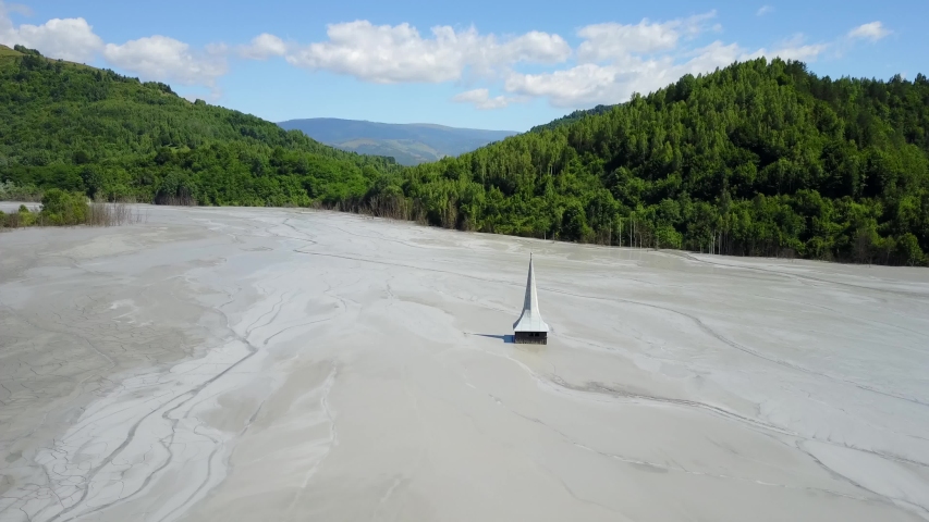Drone shot of the sunken church and grey decanting lake in Rosia Montana, the Apuseni mountains.