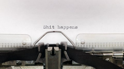 Typing a text shit happens on a vintage typewriter. Concept of motivational quote and problems solution during failure
