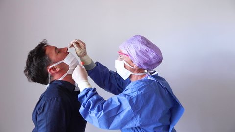 A doctor in a protective suit taking a nasal swab from a person to test for possible coronavirus infection