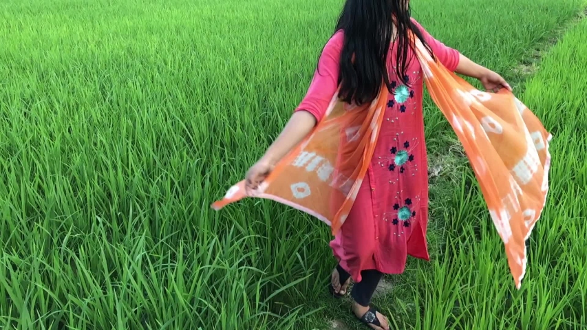 Young girl swirling in the green field