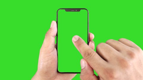 Thailand, Roi-Ed - March 23, 2020 : Man's hand holding a black smartphone with green screen and touching or press display, Man using mobile phone with chroma key touch display on green background.