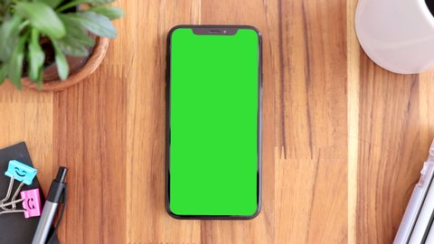 Thailand, Roi-rd - March30, 2020 : Smart phone place on table wood with green screen, Close-up the cell phone is on the brown desktop with chroma key, Green screen telephone, slider and top view. 
