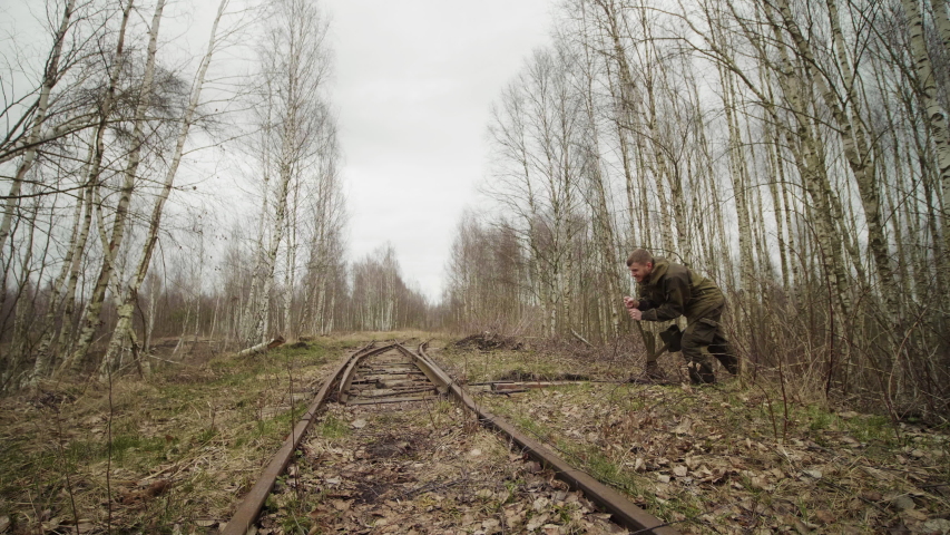 Caucasian worker swithes arrows mechanism of tracks on the railway in autumn forest