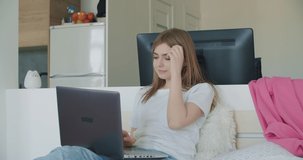 Attractive woman using her laptop computer and doing meeting or web conference from home. Freelance female model coughing . Girl sitting on bed. Self isolation. 4k video footage slow motion