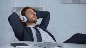 businessman with closed eyes listening music in headphones