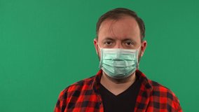 Close Up Of a Man With A Medical Mask Filmed On Chroma Key. Man Wearing Hygienic Mask. Coronavirus Protection Covid - 19. Portrait Of Medical Doctor Putting Mask On Green Background. 4K video