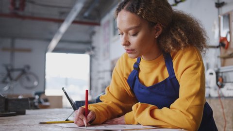 Female business owner in workshop making notes on plan for bicycle - shot in slow motion Video Stok