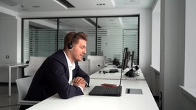 Happy businessman with laptop and headset talking during video conference