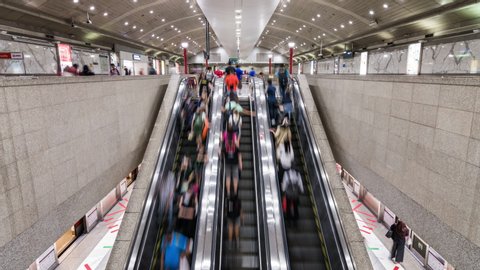 Singapore, Singapore - Feb 6, 2020: Asian people walk and use escalator at MRT subway underground station. Public transportation, Asia everyday city life, or commuter urban lifestyle concept. Tilt up