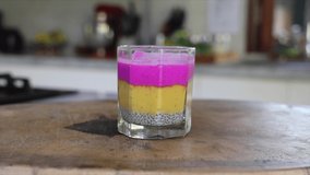 Male hands sprinkles glass of mango dragon fruit chia pudding with granola.  Isolated in the kitchen background. Healthy vegetarian breakfast isolated video footage 4K
